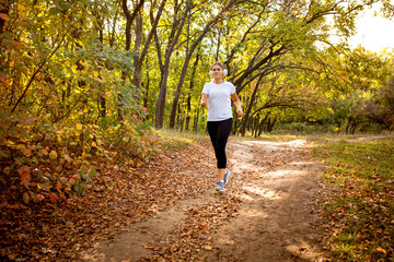 Action. Disabled woman walking down and training outdoors in forest, practicing. Active woman with...