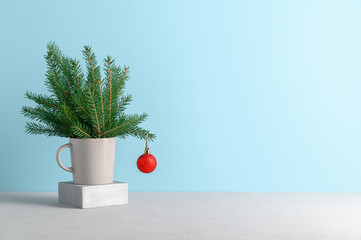 Alternative Christmas tree in gray mug decorated red ball on pastel blue background. Xmas greeting...