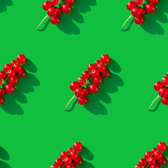 Seamless pattern with a sprig of red currant on a green background. 