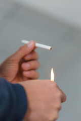 Male hand holding a lighter with a big flame and a cigarette