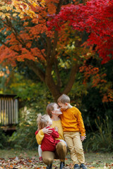 Fototapeta premium A beautiful young mother and two children are walking in the autumn park. A happy family.