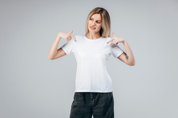 Stylish blonde girl wearing white t-shirt posing in studio