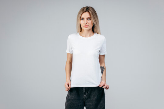 Stylish blonde girl wearing white t-shirt posing in studio
