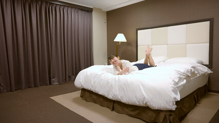 Fototapeta na wymiar ホテルのベッドの上ではしゃいでいる女性