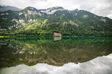 Fototapeta premium Clear blue summer day at lake Klontalersee. Glarnisch, mountain range reflecting in the water. Landscape in Switzerland.