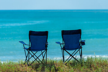 Two camping tables by the sea with turquoise water on a sunny day