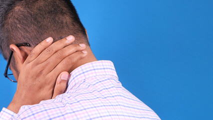 Fototapeta premium man suffering from neck or shoulder pain on blue background 