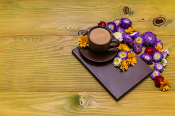 Image of cup of coffee and book with beautiful flowers  on wooden background.