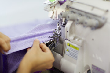 The worker is sewing a textile with a sewing machine in a fabric factory.