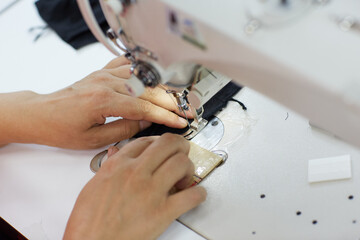 The worker is sewing a textile with a sewing machine in a fabric factory.