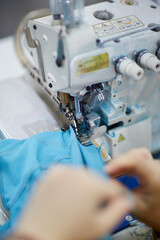 The worker is sewing a textile with a sewing machine in a fabric factory.