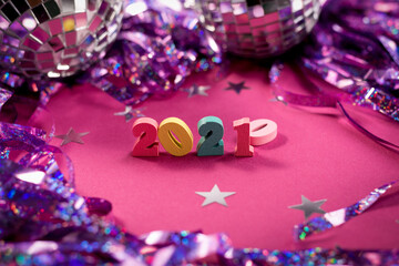 New 2021 year coming instead of 2020. Wooden numbers on a purple background among confetti and disco balls. New Year and Merry Christmas party concept.