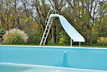 backyard swimming pool with pool slide emptied out shutting down for winter