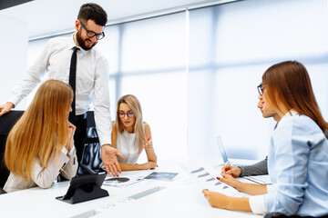 Fototapeta premium group of young leaders sitting at their desk discussing planning the next steps of work