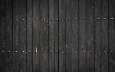 Dark gray weathered wooden door with rivets, vertical lines and space for text