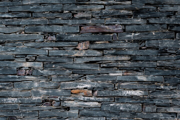 Background of slate stones forming a wall in dark tones with space for text
