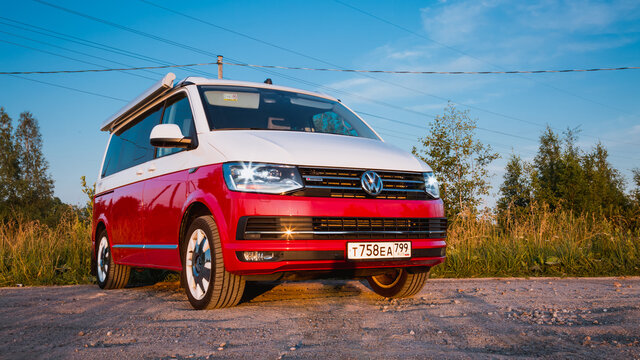 St. Petersburg, Russia - July 22, 2019: Red and white colored modern Multivan California Ocean (Transporter T6). Is parked on the country road. Front side view