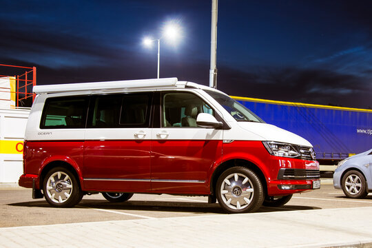 St. Petersburg, Russia - July 22, 2019: Red and white colored modern Multivan California Ocean (Transporter). Is Parked at night near the intercity highway in the background of the forest