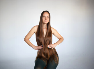 Naklejka premium young beautiful woman with very long hair sits on a chair