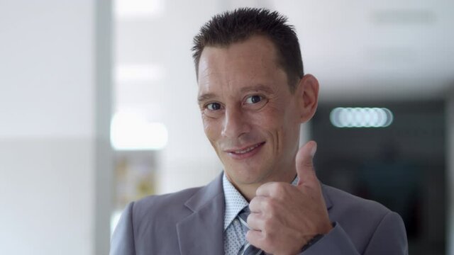Medium close up shot of a business man wearing a suit and tie short hair stylish is smiling and make him smile and raise his hand like.