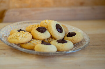 Light brown beige baked peanut cookies filled with dark chocolate, one by one on the plate, tasty Christmas sweets ready to eat
