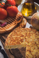 Tortilla de patatas caseras con pan tostado y cebolla, tomates y aceite