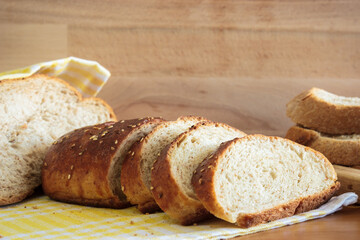 Close up homemade breads on yellow napkin wooden table in kitchen. Wooden backdrop at background. Homemade food concept.