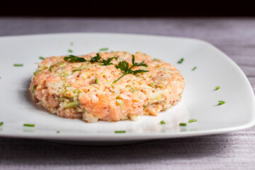 Tartar de salmón con aguacate, pepinillos y alcaparras, con mostaza en grano y decorado e cilantro con hierba