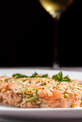 Primer plano de tartar de salmón con copa de vino de fondo difuminada