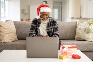 Senior man in Santa hat having a video chat on his laptop at home