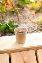 Paper cup with hot coffee on the green terrace.
Pappbecher mit heißem Kaffee auf der grünen Terrasse.