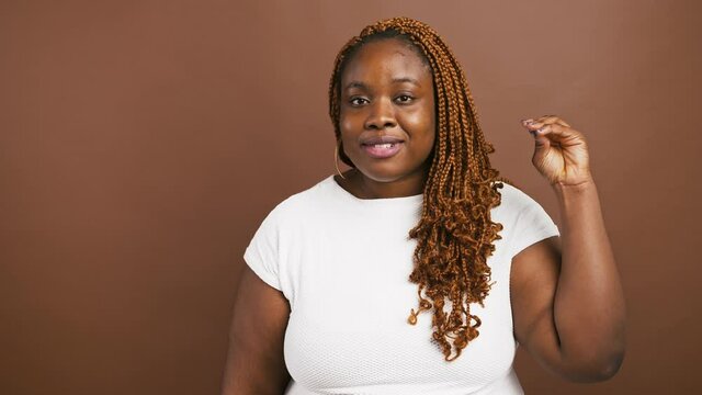 Annoyed african american woman showing bla bla bla gesture and grimacing over brown studio background