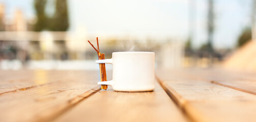 Steaming coffee in cup on terrace in urban area.
Dampfender Kaffee in der Tasse auf der Terrasse in der Stadt.