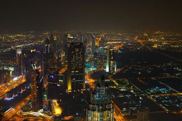 Panoramic aerial view on downtown of Dubai with modern high skyscrapers at night. Architecture of future with bright lights and roads. Famous tourist destination