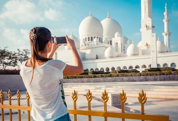 Zelfklevend Fotobehang Young tourist woman shooting on mobile phone Sheikh Zayed great white mosque in Abu Dhabi, United Arab Emirates, Persian gulf. UAE is famous tourism destination © oleg_p_100