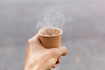 Hot cardboard cup with steaming drink in hand.
Heißer Kartonbecher mit dampfendem Getränk in der...