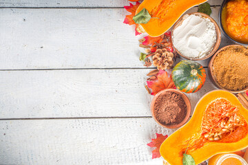 Autumn traditional baking background. Ingredients for cooking pumpkin pie, with pumpkin spice, half sliced pumpkins, flour, utensils and fall decor, top view copy space