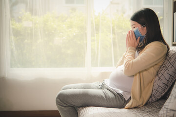 Pregnant mother Asia use face mask covering fetus or baby coronavirus, pollution, flu or pandemic. Pregnancy woman quarantine at home. afraid spread coronavirus covid 19 Pregnant mother coughing