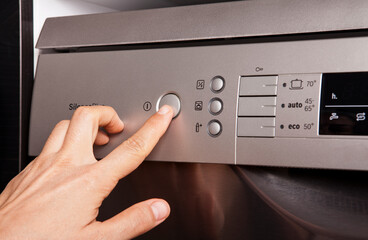 The woman puts the dishes in the dishwasher and runs it.
