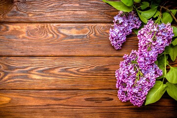 A bouquet of lilacs lies on a brown wooden background
