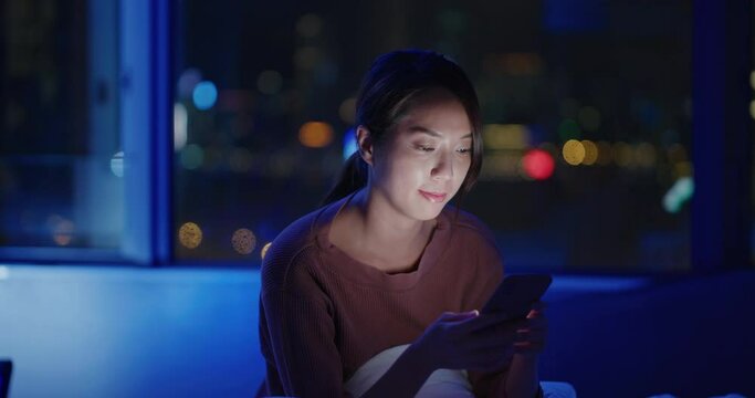 Woman use of smart phone at night inside room