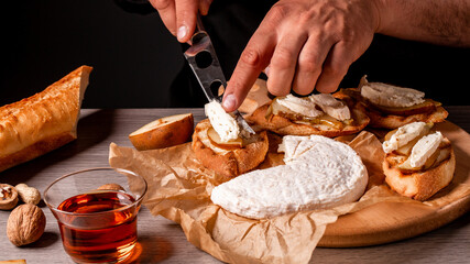 Man cooking Italian bruschetta with baked pear, honey, walnut and brie camembert cheese