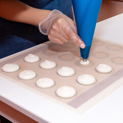 The pastry chef puts the dough in the form of macaroons from the bag on parchment. The process of making dessert.