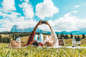 Couple of tourists lying on the grass visiting tirol alps. Boyfriend and girlfriend in love taking...