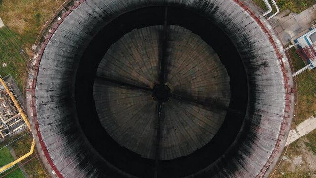 Camera rises up over huge cooling tower made of concrete blocks at contemporary heat power station in autumn aerial view