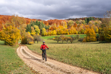 sympathetic active senior woman, riding her electric mountainbike in the gold colored autumn forests of the Swabian Alb