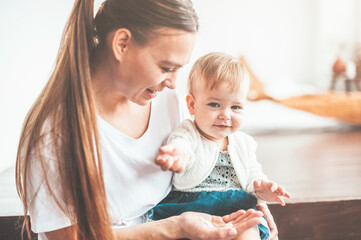 Mom and baby are sitting at home and smiling cheerfully