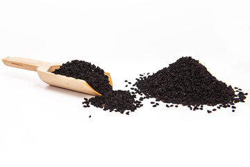 Black cumin seeds in a wooden spoon. Stack of  black cumin seedson a white background.