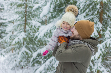 Fototapeta na wymiar Father and daughter have fun in snowy forest in winter. Enjoy to spend time together.