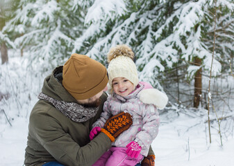 Obraz premium Little cute girl have fun with bearded father in snowy winter forest.